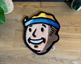 May include: A brown and beige rug with a cartoon face of a person wearing a yellow and blue hat. The rug is on a wooden floor.