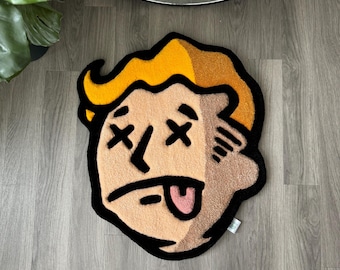May include: A round, yellow and brown rug with a cartoon face with X's for eyes and a tongue sticking out. The rug is on a wood floor.