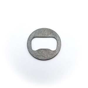 May include: A silver metal bottle opener with a round shape and a cut-out design.