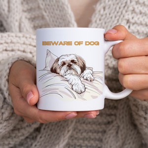 May include: White ceramic mug with a brown and white Shih Tzu dog illustration lying on a pillow. The text "BEWARE OF DOG" is printed in orange on the mug.