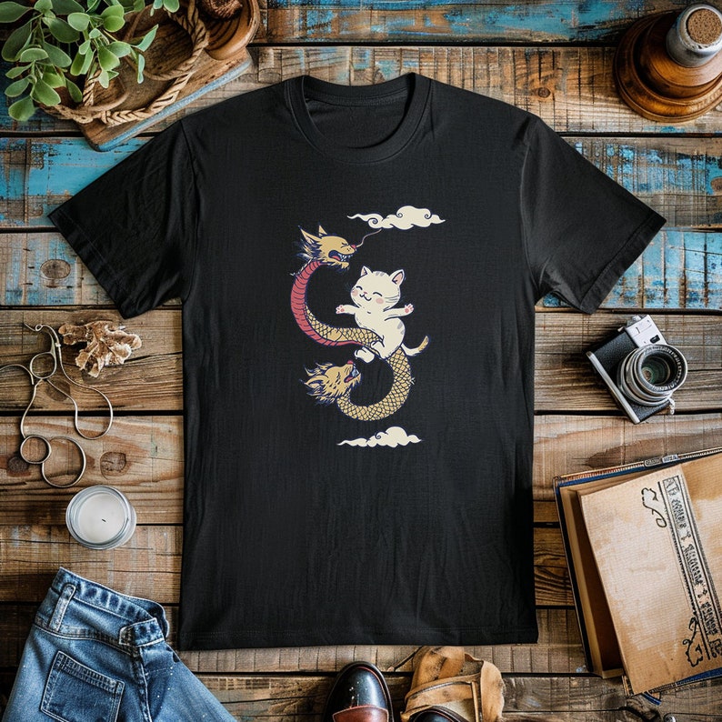 K&ouml;nnte beinhalten: Schwarzes T-Shirt mit einem Aufdruck eines wei&szlig;en Katers, der auf einem roten und gelben Drachen reitet.