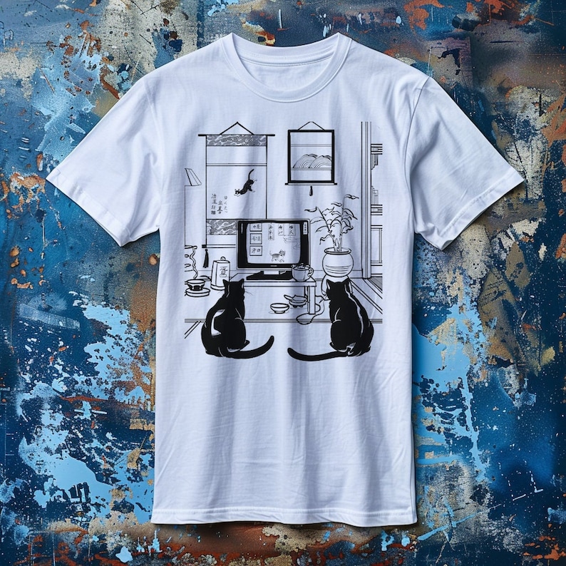 May include: White t-shirt with a black and white illustration of two cats watching television in a room with a potted plant, a painting, and a bookshelf. The text on the television reads "The Cat's Meow".