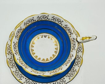 May include: A blue and white teacup and saucer with gold trim and a scalloped edge. The cup and saucer feature a delicate floral pattern.