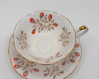 Può includere: Un set da tè bianco con una delicata fantasia floreale in tonalità arancio e oro. La tazza e il piattino hanno un bordo ondulato e un bordo dorato.