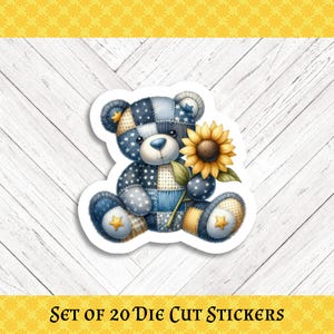 May include: A die-cut sticker featuring a patchwork teddy bear in shades of blue, holding a sunflower. The bear has star accents and is set against a white background. The text "SET OF 20 DIE CUT STICKERS" is at the bottom.