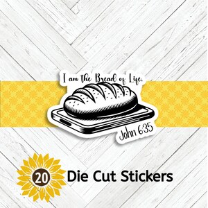 May include: Die-cut sticker featuring a black and white illustration of a loaf of bread on a cutting board, with the text "I am the Bread of Life" and "John 6:35". The sticker is set against a white wood background with a yellow accent.