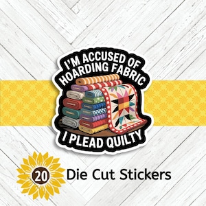 May include: A die-cut sticker featuring a stack of colorful fabric bolts and a quilt with a star pattern. The text reads I'M ACCUSED OF HOARDING FABRIC I PLEAD QUILTY in bold white letters against a black background. The design includes various patterns.