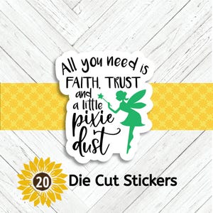 May include: White die-cut sticker with the text "All you need is FAITH, TRUST and a little pixie dust." A green fairy with a wand is also featured. The sticker is on a white wood background with a yellow floral design.