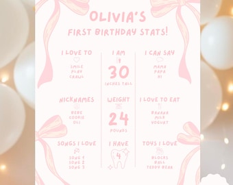 May include: A pink and white birthday stats sign for Olivia, with bow illustrations. The sign includes the text "Olivia's First Birthday Stats!" and details such as height (30 inches), weight (24 pounds), and favorite things.