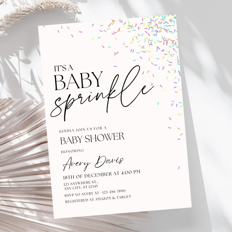 May include: A white baby shower invitation with a colorful sprinkle design. The text reads "It's a Baby Sprinkle" and includes the name "Avery Davis", the date "18th of December", the time "4:00 PM", the address "123 Anywhere St., Any City, ST 12345", the RSVP number "123-456-7890", and the registry information "Registered at Amazon & Target".