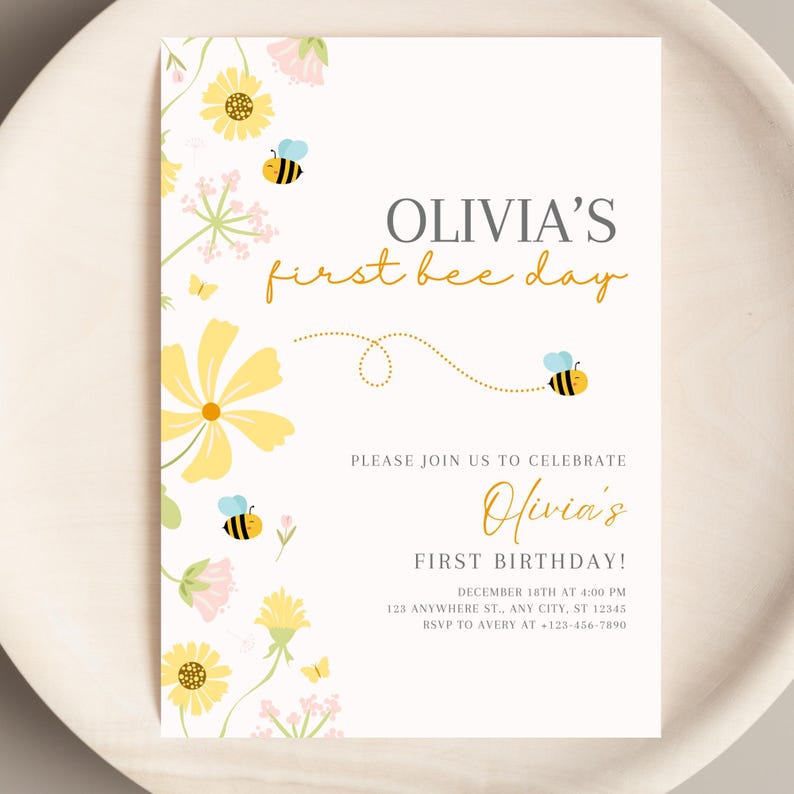 May include: A cream-colored invitation with floral and bee illustrations. The text reads "OLIVIA'S first bee day" and "Olivia's FIRST BIRTHDAY!" with event details. Yellow and pink flowers and bees decorate the corners.