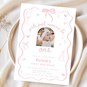 Pode incluir: Um convite de aniversário rosa e branco com o texto "girls just wanna be one". O convite inclui uma foto de um bebê e detalhes para o primeiro aniversário de Olivia, incluindo a data, hora e local.
