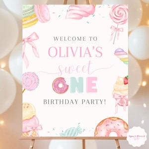 May include: A party sign on an easel with the text "Welcome to Olivia's Sweet One Birthday Party!" The sign features watercolor illustrations of sweets, including donuts, lollipops, and ice cream cones, in pastel pink, yellow, and blue colors.