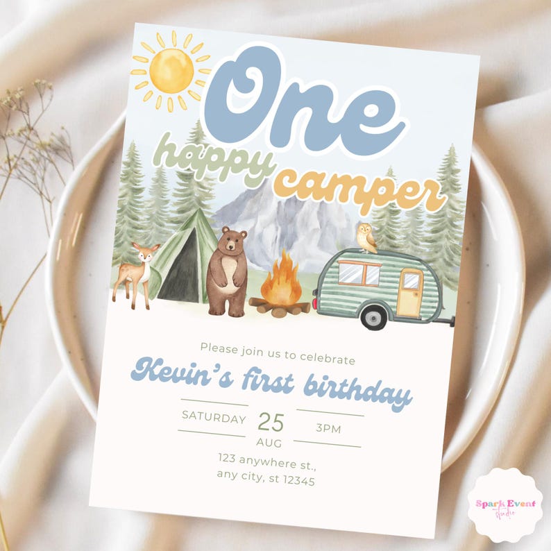 May include: A blue and yellow birthday invitation with a watercolor illustration of a campsite. The invitation says "One happy camper" and includes the text "Please join us to celebrate Kevin's first birthday. Saturday, August 25, 3PM. 123 anywhere st., any city, st 12345."