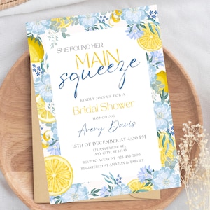 Puede incluir: Una invitación de ducha nupcial blanca con un diseño de limón y flores. El texto dice "She found her main squeeze" e incluye detalles del evento, incluida la fecha, la hora y la ubicación. La invitación también incluye el nombre de la novia, Avery Davis, e información sobre dónde RSVP y dónde está registrada la novia.