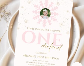 May include: Pink and gold first birthday invitation with a snowflake design and a photo of a baby girl. The invitation says "Please join us for a winter one-derland celebrating Melanie's first birthday!" with the date and time of the party and RSVP information.