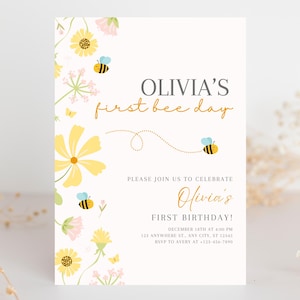 Könnte beinhalten: Eine cremefarbene Einladung mit Blumen- und Bienenillustrationen. Der Text lautet "OLIVIA'S first bee day" und "Olivia's FIRST BIRTHDAY!" mit Veranstaltungsdetails. Gelbe und rosa Blumen und Bienen schmücken den Rand.