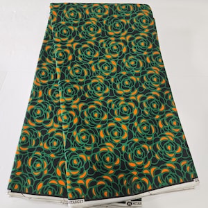 Puede incluir: Tela verde y naranja con un patrón repetido de rosas estilizadas. La tela está doblada por la mitad.