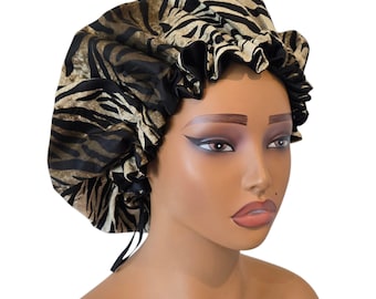 May include: A black and gold zebra print satin bonnet with a ruffled edge. The bonnet has a drawstring closure and is designed to protect hair. The fabric has a shiny appearance.