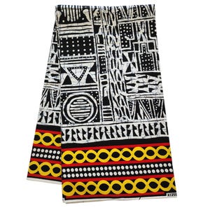 May include: Folded fabric with a bold black and white geometric pattern. The design includes circles, triangles, and rectangular shapes. The bottom edge features a border of yellow circles, red lines, and white dots.