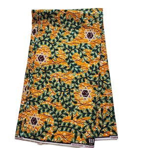 May include: Folded fabric featuring a yellow backdrop with a repeating pattern of green leaves and star motifs. The fabric has a textured finish and a white border with the text "VIP REGISTERED TRADEMARK". The design is eye-catching and detailed.