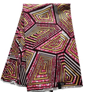 以下が含まれることがあります： ピンク、ゴールド、黒、白の幾何学模様の折り畳まれた生地。デザインは、入れ子になった角張った形状が特徴です。生地には「GUARANTEED SUPER」と「LES LA PRESTIGE NAS01622」の文字が入っています。