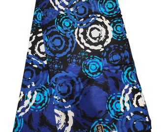 May include: Folded fabric with a vibrant pattern of blue, white, and black concentric circles. The design features varying shades of blue, creating a dynamic and eye-catching visual effect. The fabric appears to be a medium weight, suitable for various sewing projects.