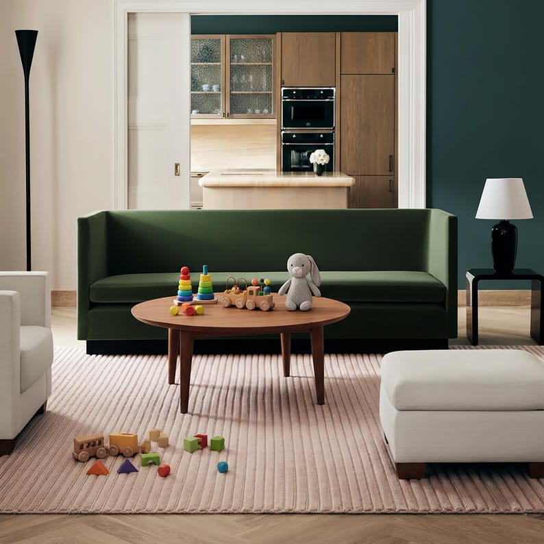 May include: A living room scene featuring a green sofa, a round wooden coffee table with children's toys, and a light pink rug. A gray stuffed bunny sits on the table. A white ottoman and a black lamp are also visible.
