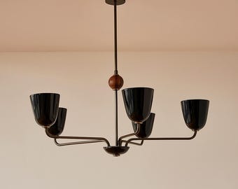 May include: A modern chandelier with five black, bell-shaped shades. The fixture has a dark bronze finish with a wooden sphere accent. The light hangs from a central rod, with arms extending to hold the shades.