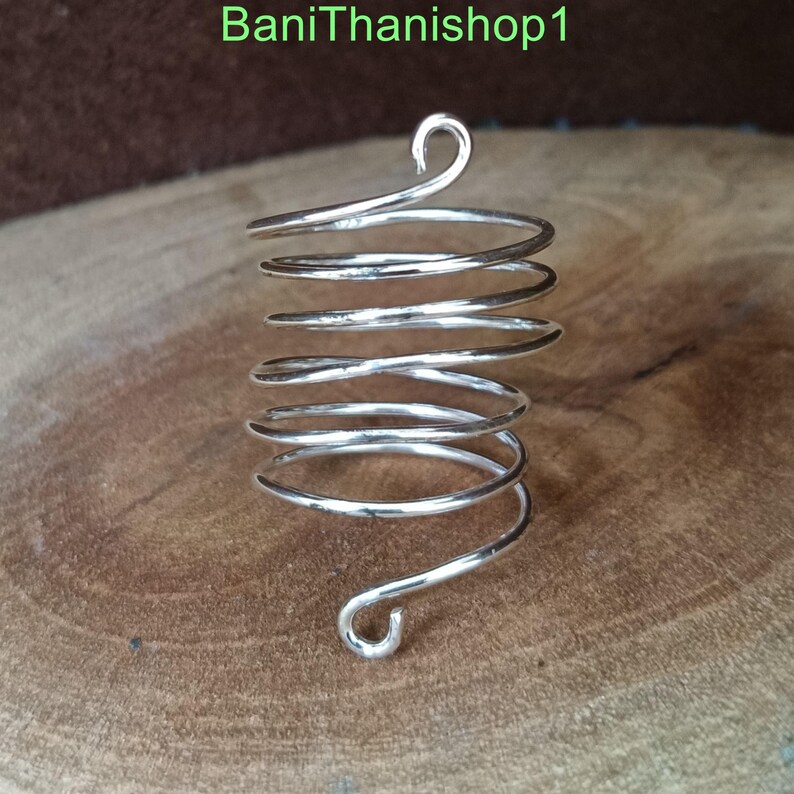 Puede incluir: Un anillo de espiral de plata con un dise&ntilde;o &uacute;nico. El anillo est&aacute; hecho de un solo alambre que se tuerce en forma de espiral. El anillo est&aacute; abierto y se puede ajustar para que se ajuste a diferentes tama&ntilde;os de dedos.