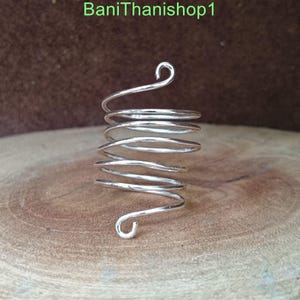 Puede incluir: Un anillo de espiral de plata con un dise&ntilde;o &uacute;nico. El anillo est&aacute; hecho de un solo alambre que se tuerce en forma de espiral. Los extremos del alambre se doblan en bucles, que se pueden usar para ajustar el tama&ntilde;o del anillo.