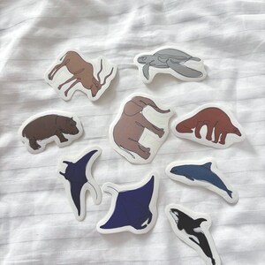 May include: A selection of animal stickers. The stickers depict a range of creatures, such as a turtle, elephant, and orca. Each sticker has a white border and is set against a white background.