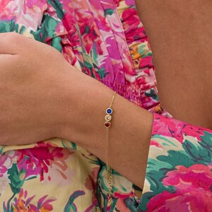 May include: A gold chain bracelet with three small round stones in red, blue, and yellow.