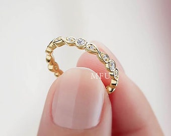 May include: A delicate gold band ring with a row of small, round clear stones set in a wavy pattern.