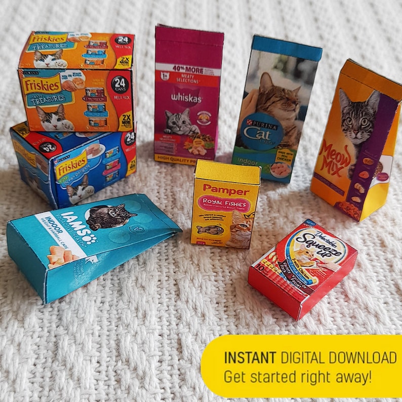 Pode incluir: Conjunto de marcas de comida para gatos em caixas em miniatura, incluindo Friskies, Whiskas, Purina Cat, Meow Mix, IAMS, Pamper e Delectables Squeeze Up. As caixas est&atilde;o dispostas sobre uma superf&iacute;cie de malha branca.