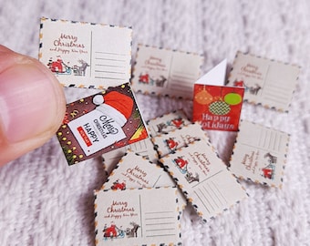May include: A collection of miniature Christmas cards with various designs, including a red Santa hat, a reindeer, and a Christmas tree. The cards are printed with the text "Merry Christmas and Happy New Year" and "Happy Holidays".
