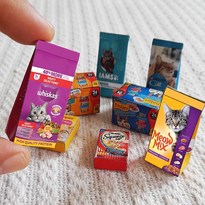 Pode incluir: Conjunto de marcas de comida para gatos, incluindo Whiskas, IAMS, Friskies, Meow Mix e um saco vermelho com o texto "Delectable Squeeze Up".