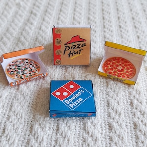 May include: Three miniature pizza boxes, one each for Domino's Pizza, Little Caesars Pizza, and Pizza Hut. The boxes are open and show a small pizza inside each.
