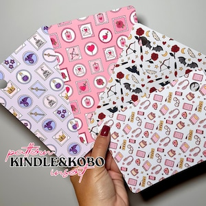 Può includere: Quattro inserti Kindle e Kobo a fantasia tenuti in mano. Gli inserti presentano motivi ripetuti di francobolli, cuori, rose e altri elementi decorativi in rosa, viola e bianco. Il testo "pattern KINDLE & KOBO insert" è visibile.