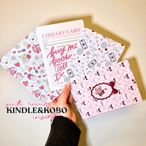 Può includere: Un set di inserti Kindle e Kobo con vari motivi. Un inserto presenta un design di scheda della biblioteca con il testo "buy me book tell I'm". Altri inserti hanno motivi di cuori, fiocchi e altri elementi decorativi. È visibile anche il testo "gentle reader KINDLE & KOBO insert".
