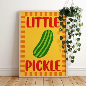 May include: A yellow and orange striped poster with the text "LITTLE PICKLE" in red letters. A green pickle is in the centre of the poster.