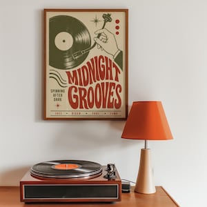 May include: A framed wall poster titled Midnight Grooves featuring a graphic illustration of a hand placing a needle on a vinyl record. The text reads Midnight Grooves, Spinning After Dark, and lists the genres Jazz, Disco, Soul, and Funk.