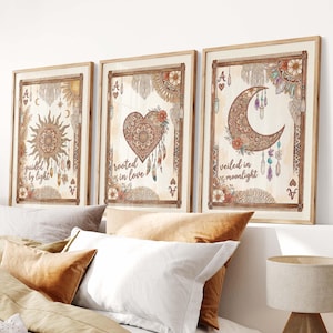 May include: Three framed art prints with bohemian designs. The prints feature a sun, a heart, and a crescent moon, each with intricate details and text. The colour palette includes warm earth tones and soft pastels, creating a serene and artistic aesthetic.