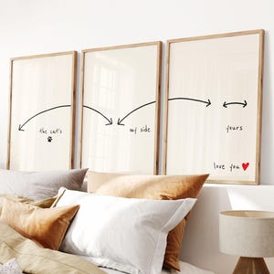 Op de afbeelding: Drie ingelijste kunstdrukken met een lichtbeige achtergrond en houten frames. De prints bevatten handgeschreven tekst en pijlen. De eerste print zegt "the cat's" met een pootafdruk. De tweede zegt "my side". De derde zegt "yours" en "love you" met een rood hart.