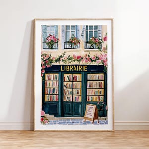 May include: Watercolour print of a bookstore facade with the word "LIBRAIRIE" above the entrance. The building has teal doors and windows, with flower boxes and pink roses. A wooden framed sign stands in front.