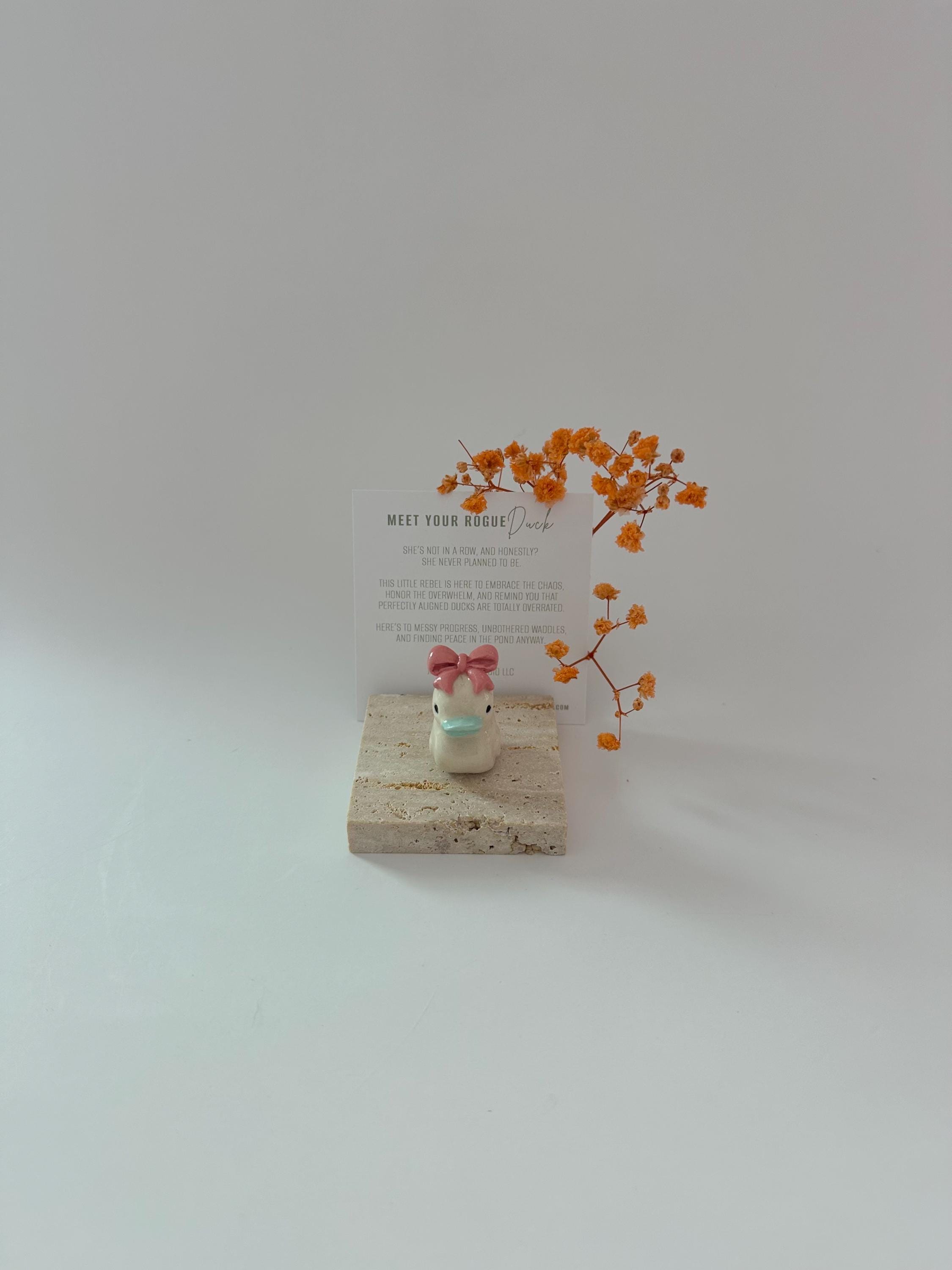 ピンクのリボンが付いた手作りの陶器製アヒルの置物：デスク