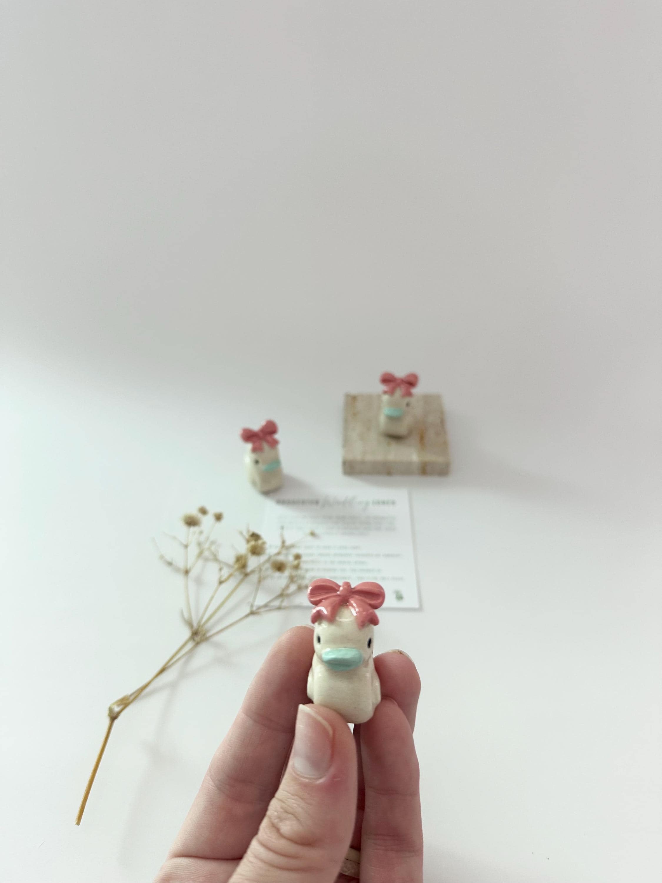 ピンクのリボンが付いた手作りの陶器製アヒルの置物：デスク