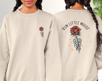May include: A beige sweatshirt with a rose and skeleton hand graphic on the front and the text "RUN LITTLE MOUSE" on the back.