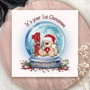 Tarjeta de felicitación personalizada "Es tu primera Navidad". Globo navideño festivo. Tarjeta navideña personalizable con forma de globo de nieve.