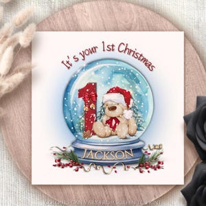 Tarjeta de felicitación personalizada "Es tu primera Navidad". Globo navideño festivo. Tarjeta navideña personalizable con forma de globo de nieve.